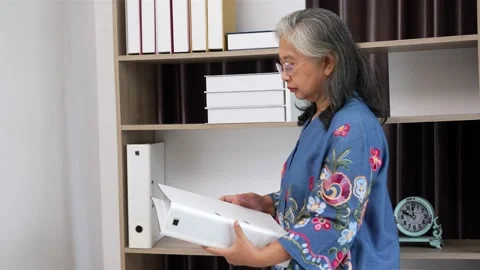 Senior woman finding paperwork in folder on shelf at home Stock Footage 154845309