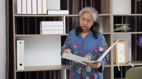 Senior woman finding paperwork in folder on shelf at home Stock Footage 154845356