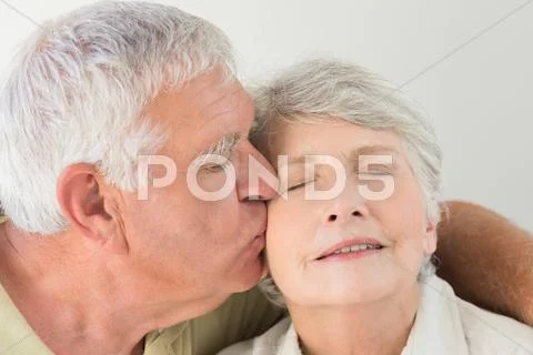 Senior Woman Getting A Kiss On The Cheek From Partner