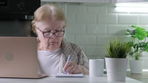 Senior woman in glasses working using laptop with serious face at home Video stock 171556915