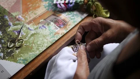 Senior Woman Hands Doing Cross Stitch on White Cotton Fabric. 4K, Close Up. Stock Footage