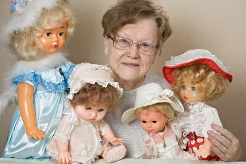 A senior woman with her collection of old-fashioned dolls Stock Photos