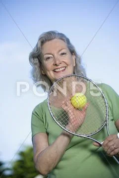 A senior woman holding a tennis racket and ball Stock Photos