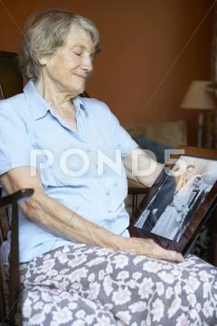 Senior woman at home looking at old wedding photo Stock-Fotos