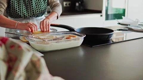 Senior woman on the kitchen soaking bread in milk and egg to make torrijas Stock Footage 261726441