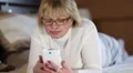 Senior woman lies on the sofa and listens to music with closed eyes HD Footage