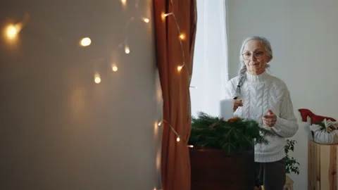 Senior woman lighting up candle at Christmas wreath indoors at home. Stock Footage