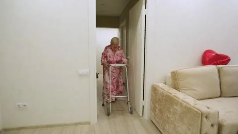 Senior woman with limited mobility using walking frame to move around her home Stock Footage 342069309