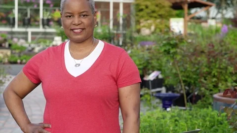 Senior woman looking at camera while standing in a garden 動画素材 83390877