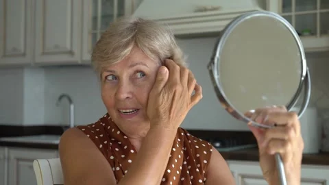 Senior woman looking at herself in the mirror Stock Footage 248344853