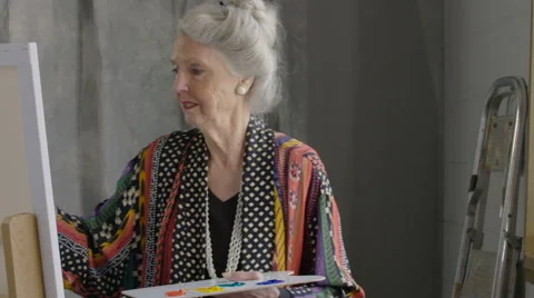 Senior woman painting at an easel in a studio Stock Footage
