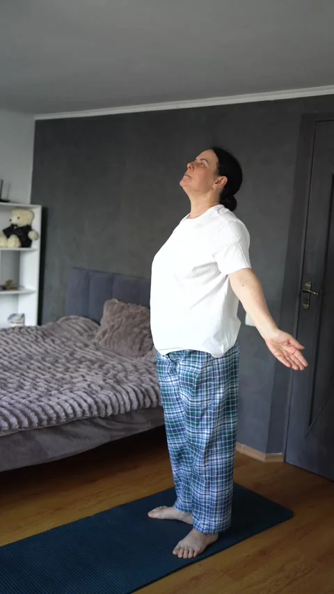 Senior woman performs somatic exercises, yoga at home Stock Footage 297485083