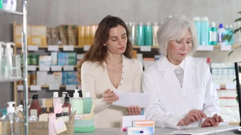 Senior woman pharmacist at computer communicate with female client Stock Footage 341783886