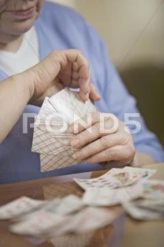 A senior woman playing cards, midsection, focus on hands Stock Photos