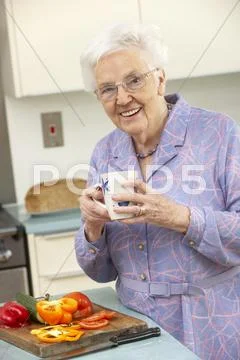 Senior woman preparing food in domestic kitchen Stock-Fotos