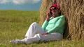Senior woman sits near haystack and communicates via mobile phone HD Footage