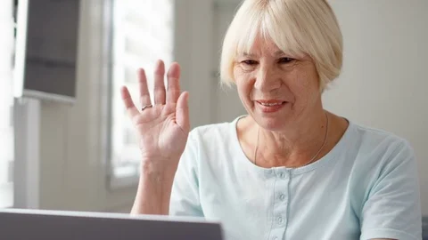 Senior woman sitting at home with laptop. Using computer talking via messenger Stock Footage