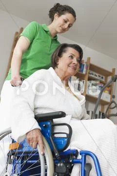 Senior woman sitting on wheelchair while another woman pushing Stock-Fotos