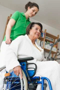 Senior woman sitting on wheelchair while another woman pushing Stock Photos