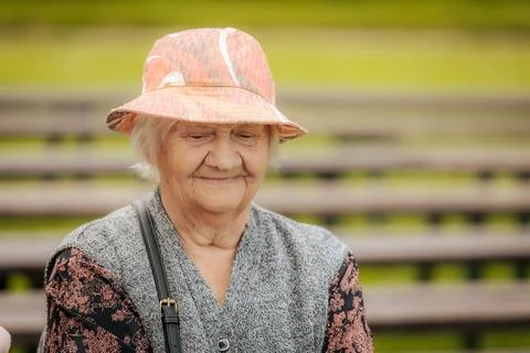 Senior woman smiling while wearing a floral dress, beaded necklace. Stock Photos