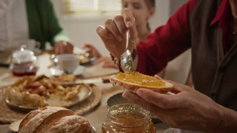 Senior Woman Spreading Jam on Bread during Family Breakfast Stock Footage 344553670