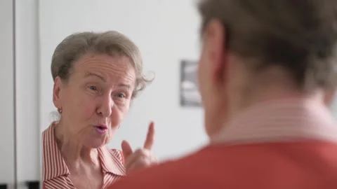 Senior woman talking to herself while looking in the mirror, close-up Vidéo 336027073