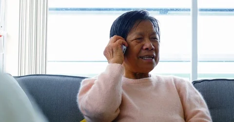 Senior woman talking on mobile phone in living room Stock Footage