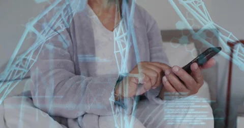 Senior woman tapping smartphone while sitting on bed, initiating blue code Stockbeeldmateriaal 332285199
