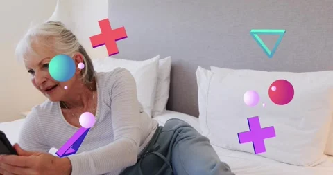 Senior woman tapping tablet while shifting posture on bed and displaying Stock Footage 320415925