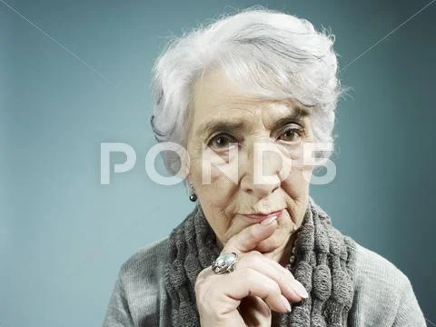 A senior woman thinking with her index finger to her lips Stock Photos