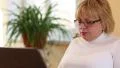 Senior woman types text uses laptop. Woman with notebook HD Footage