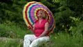 Senior woman with umbrella sits on a fallen tree in the forest HD Footage