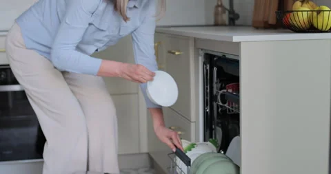 Senior woman unloading dishwasher at home. 库存影片 334066341