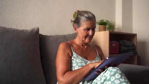 Senior woman using digital tablet on sofa Stock Footage 303856527