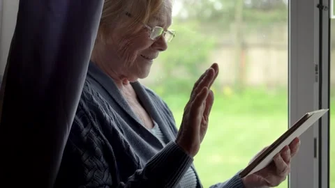 Senior woman using digital tablet through natural daylight at window Stock Footage 322061654