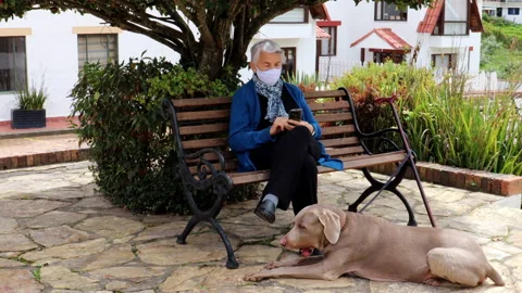 Senior woman using her cell phone wearing a home made face mask Video stock 132086341