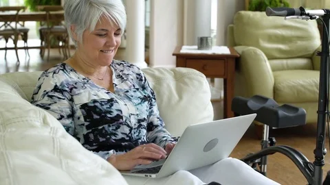 Senior woman using laptop while sitting on a couch Stock Footage 83414099