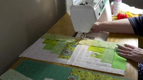 Senior woman using a sewing machine to stitch together quilt blocks Stock Footage 171453542