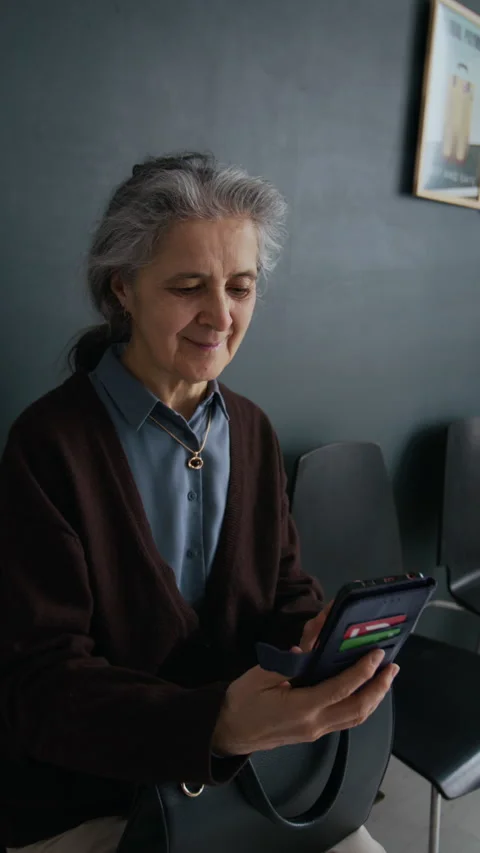 Senior Woman Using Smartphone While Waiting in Queue in Bank Office Stock Footage 310137539
