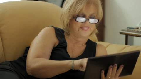 Senior woman using tablet computer at home on sofa Video stock 32361576