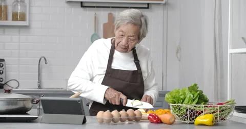 Senior woman using the tablet for looking at cooking method in modern kitchen. Video stock 148734376