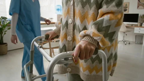 Senior Woman Using Walker in Care Home with Nurse in Background Stock Footage 337627437