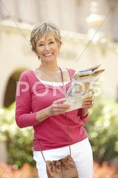 Senior Woman Walking Through City Street With Map Stock Photos