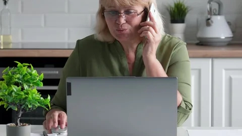 Senior woman working remotely while managing phone calls Stock Footage 315982659