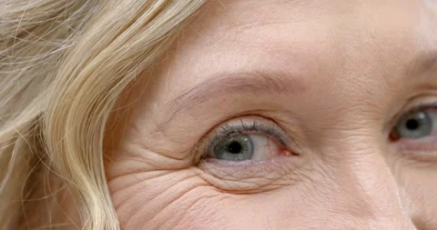 Senior woman's eye is blinking, narrowing, relaxing in studio from camera focus Stock Footage 344405740