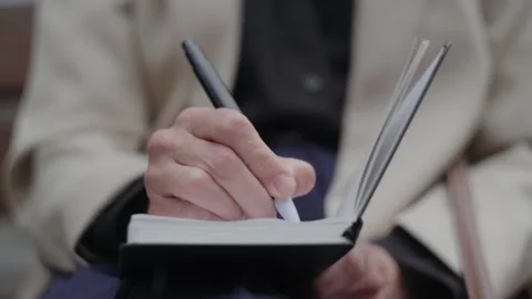 Senior Woman's Hand Writing in a Notebook Outdoors Stock-Footage 333240124