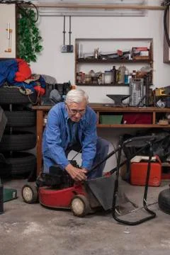 Senior worker with lawn mower in workshop Stock Photos