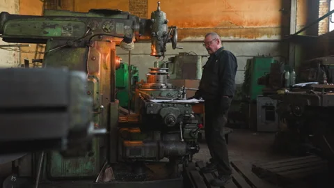 Senior worker with mustache controls drilling machine work Stock Footage 243306391