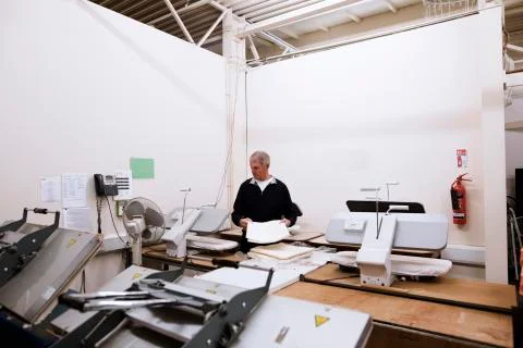 Senior Worker Pressing Tablecloths Stockfoto's