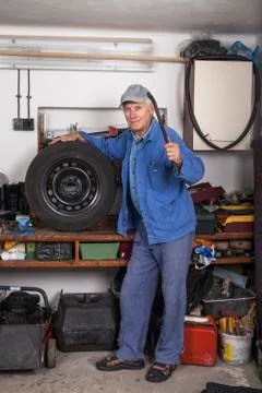 Senior worker with a tire in garage Stock Photos